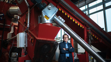 Prof. Dr. Christian Malek unter einem Biomasseheizkessel (Bild: Costa Belibasakis/TH Köln)