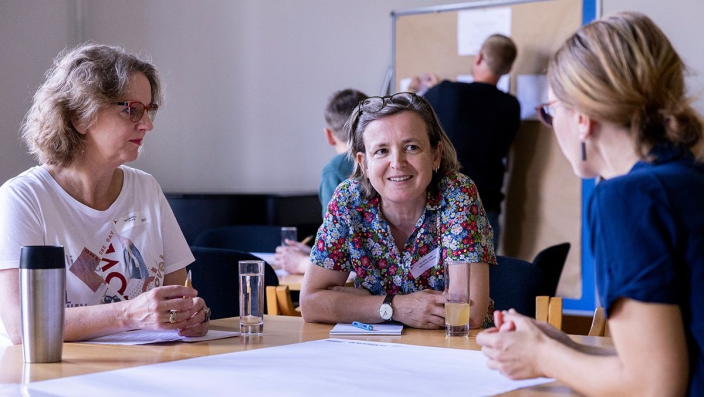 drei Frauen unterhalten sich an einem Gruppentisch