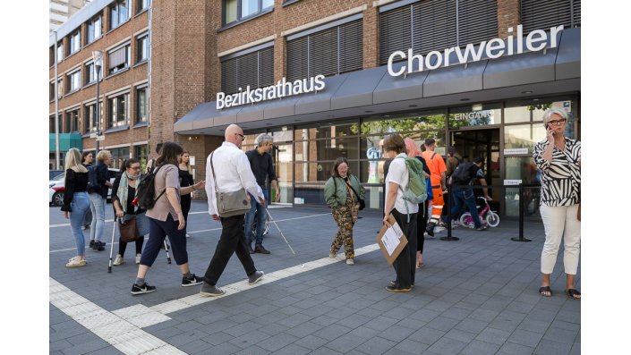 mehrere Personen stehen vor dem Eingang des Bezirkrathaus Chorweiler