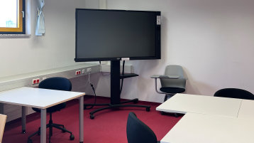 Blick in den Schulungsraum: Zu sehen sind verschiedene Sitzgelegenheiten, Tische und das mobile Smartboard (Bild: TH Köln/ Alina Beier)