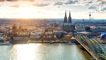 Man sieht Köln bei Tageslicht von oben, der Dom prominent in der Mitte, die Hohenzollernbrücke und angrenzende Gebiete. (Image: Adobe Stock / Simon) Man sieht Köln bei Tageslicht von oben, der Dom prominent in der Mitte, die Hohenzollernbrücke und angrenzende Gebiete. (Image: Adobe Stock / Simon)