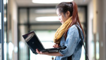 Eine Studentin steht mit einem Laptop im Flur (Bild: Thilo Schmülgen/FH Köln)