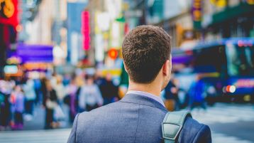 Ein junger Mann im Anzug mit Umhängetasche auf dem Weg ins Büro (Bild: Saulo Mohana auf unsplash)